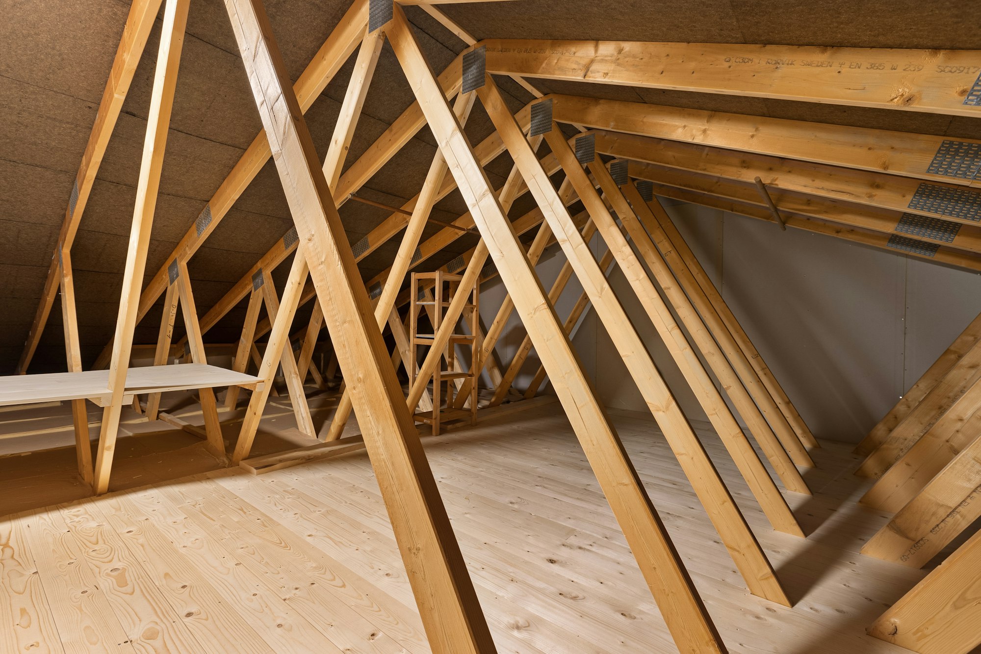 A finished loft with fully boarded floor and clean timber trusses, lit by natural light